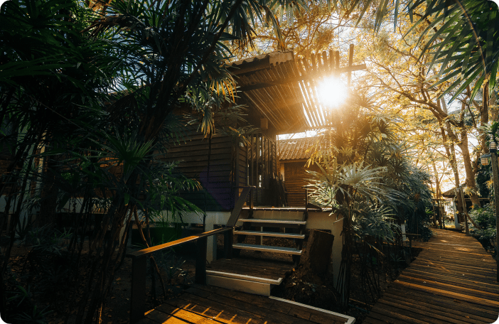 A villa lit warmly at dusk among palms